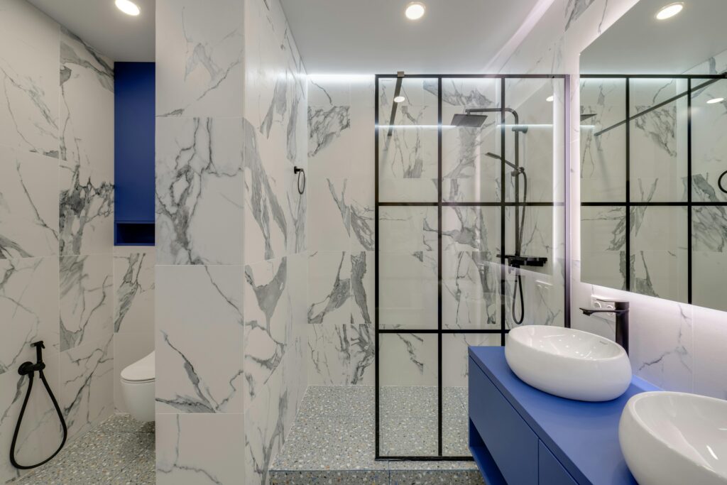 Elegant bathroom featuring marble walls, double sinks, and a glass-enclosed shower.