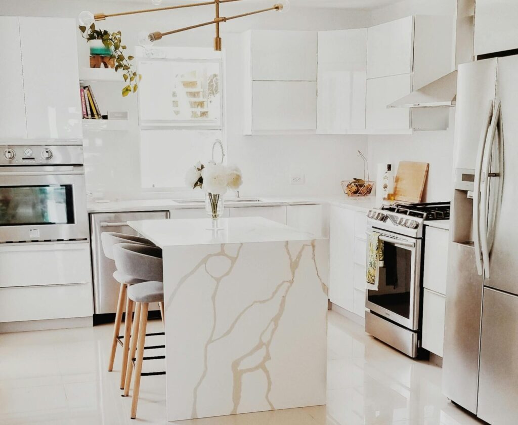 A bright, modern kitchen featuring white cabinetry, stainless steel appliances, and minimalist decor.